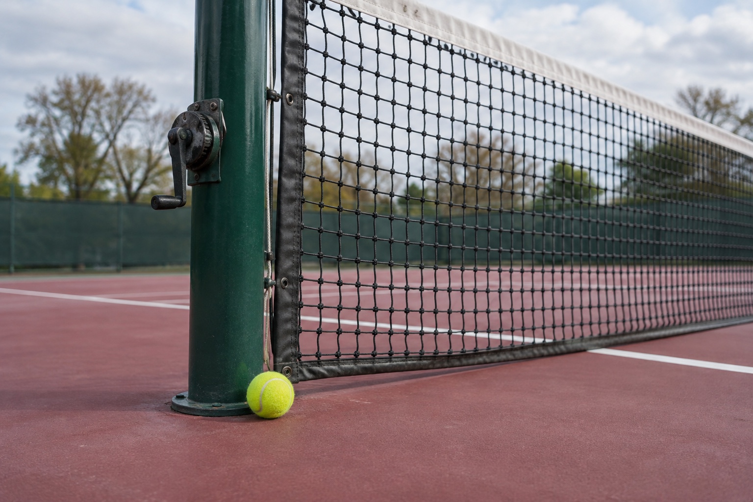 Illustration conceptuelle d'une balle de tennis à côté d'un poteau de filet vert sur un court en dur.
